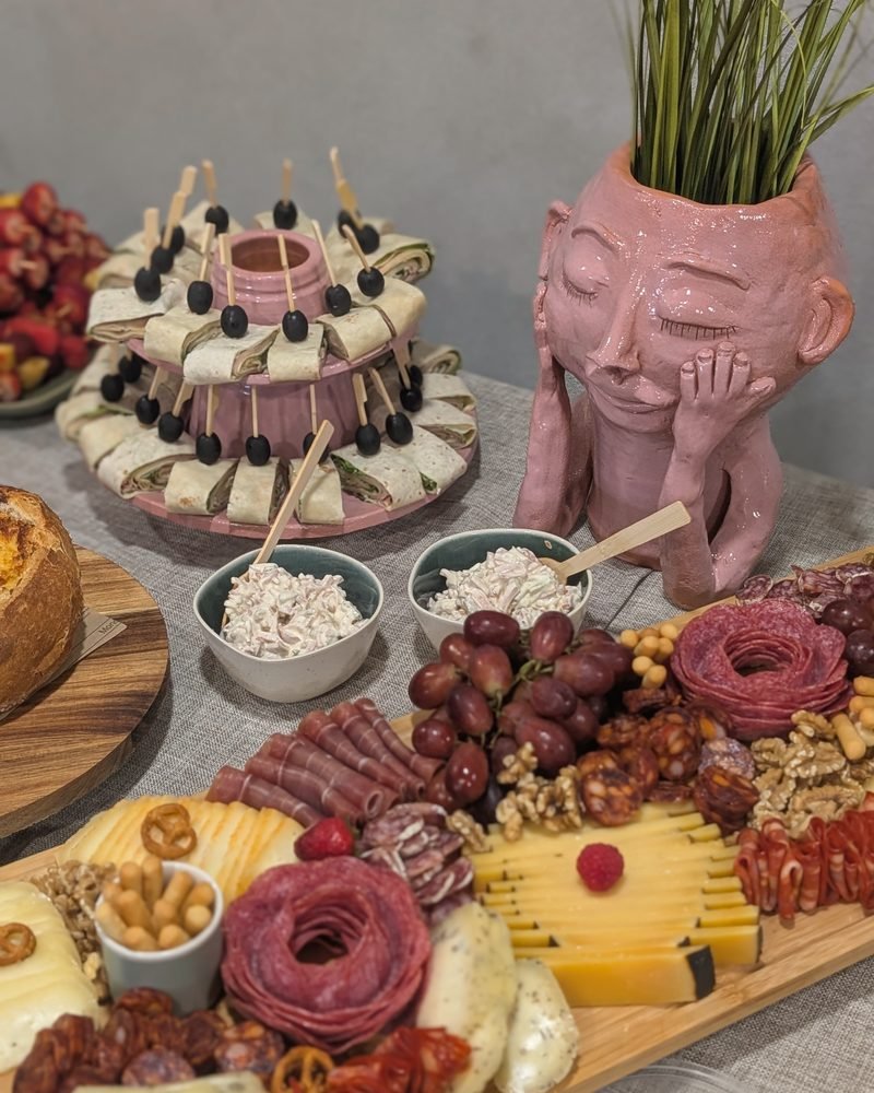 Mesa de catering com tábua de queijos e enchidos e torre de sandes