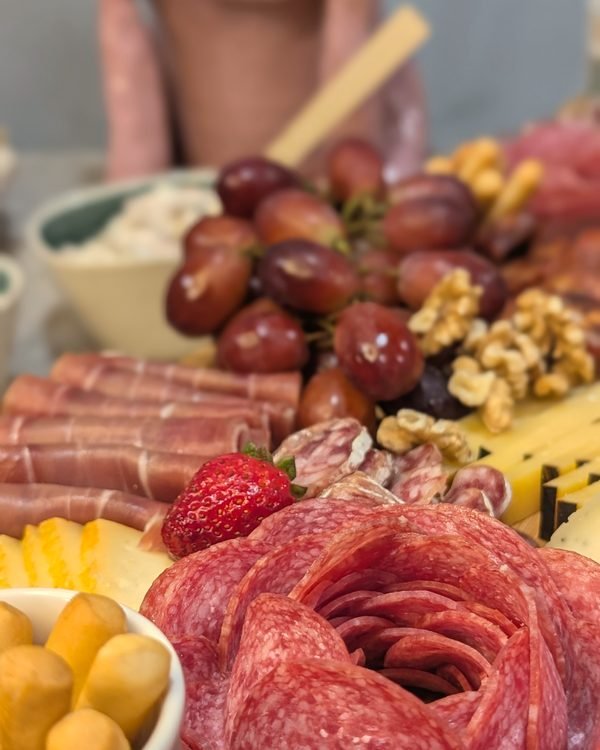 Rosa de salame, queijos e frutos numa tábua