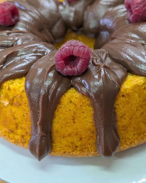 Bolo de cenoura com brigadeiro a ser decorado com framboesas