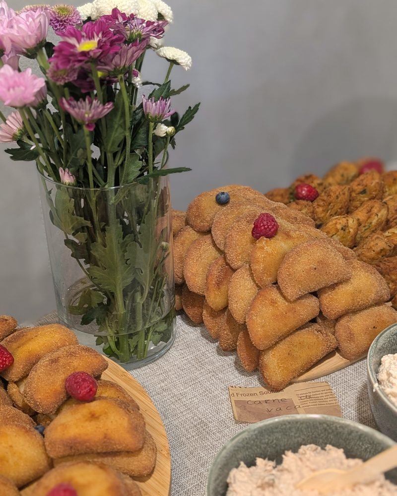 Flores frescas, rissóis caseiros e patê numa mesa de festa